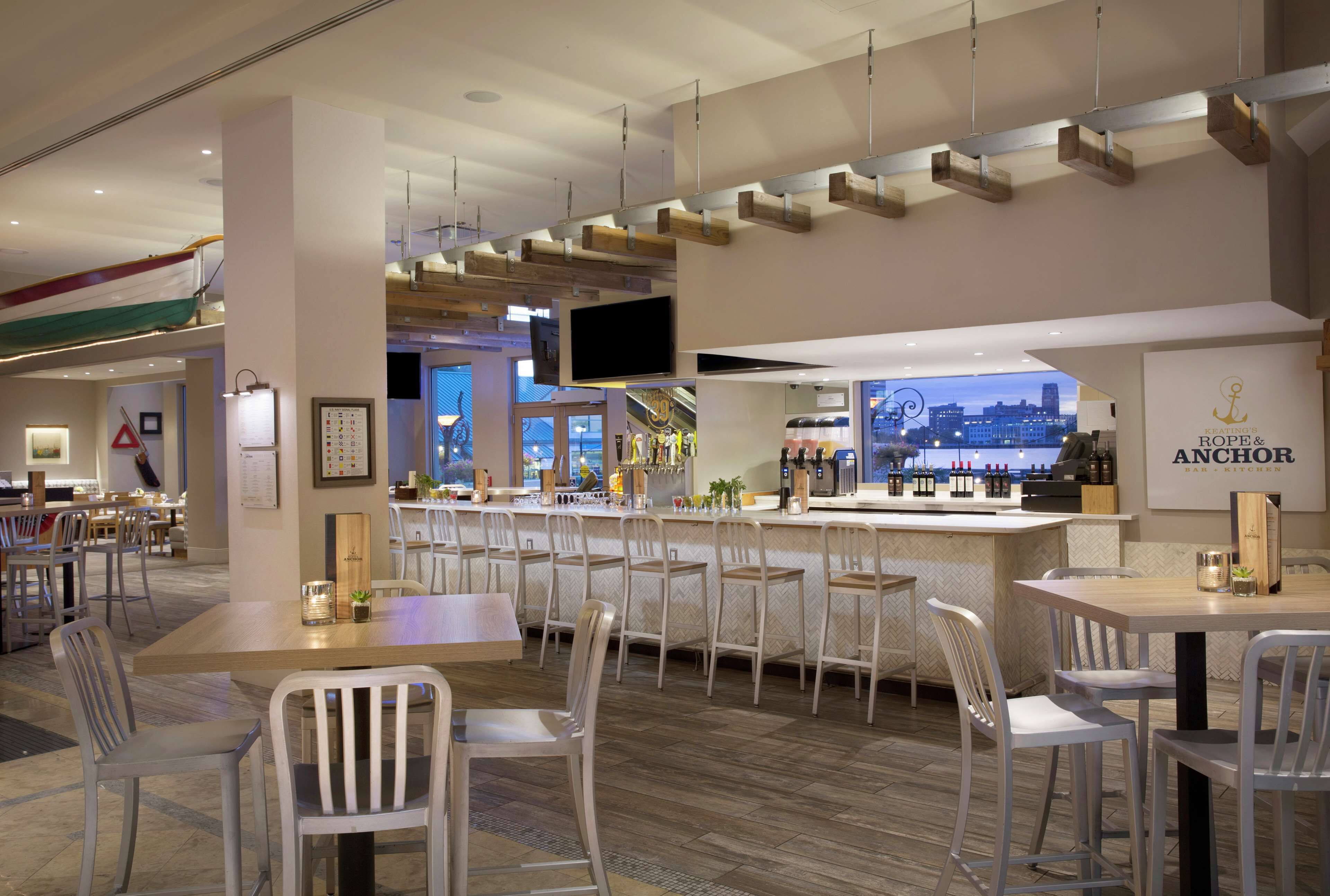 A modern bar area with a bar counter, seating, and a large screen.