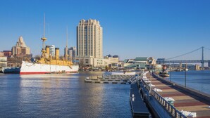 A waterfront cityscape with a large ship docked at the pier, a bridge in the background, and a tall building. - Hilton Philadelphia at Penn's Landing (Philadelphia)