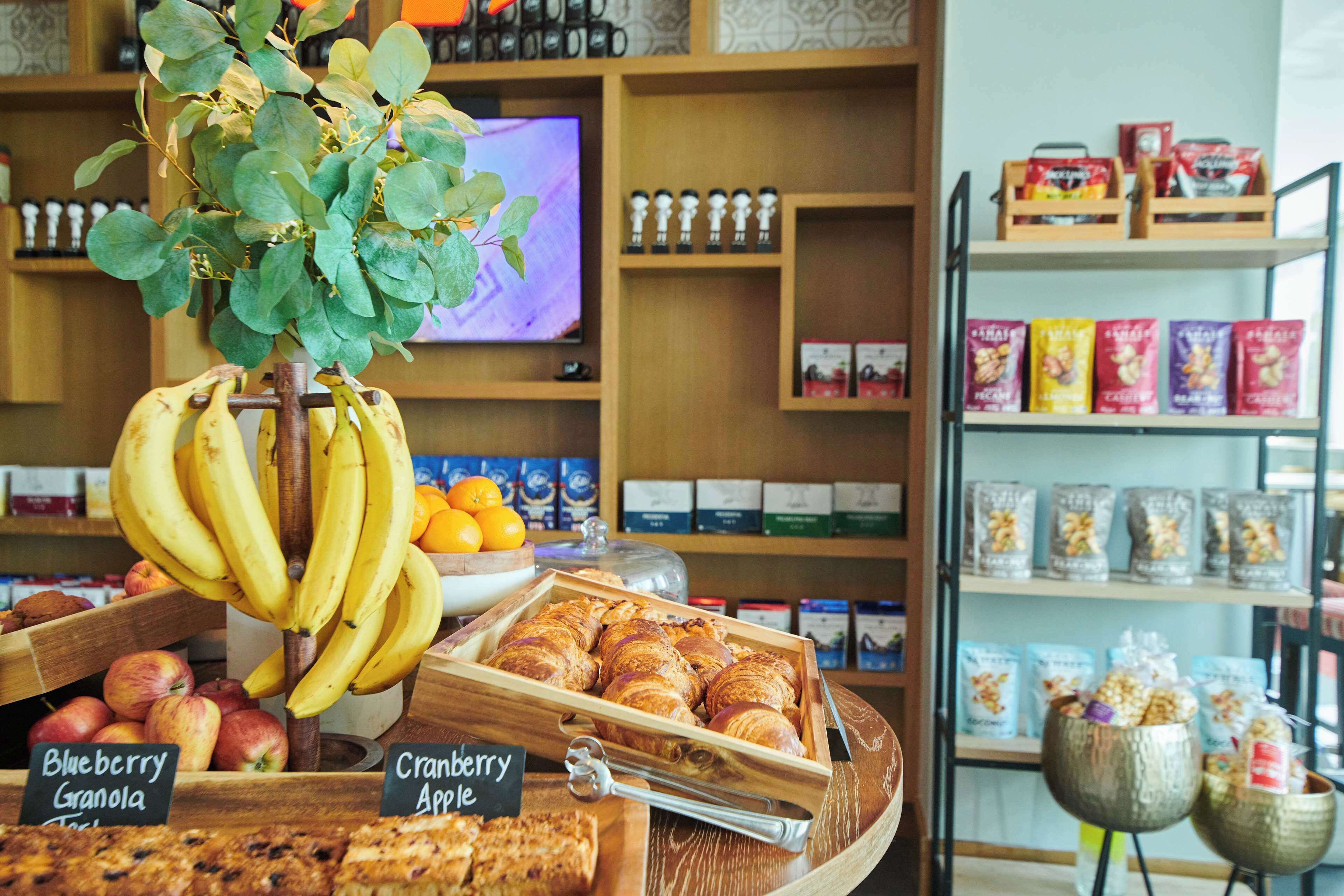 A bakery display with bananas, apples, and pastries.