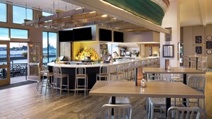 A modern bar area with a long counter, bar stools, and a view of the river. - Hilton Philadelphia at Penn's Landing (Philadelphia)