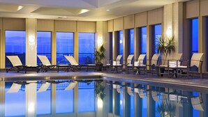 A modern indoor pool area with lounge chairs and potted plants. - Hilton Philadelphia at Penn's Landing (Philadelphia)