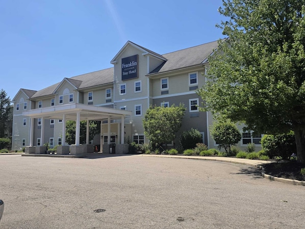 Un hotel de varios pisos con entrada cubierta y un letrero que dice 'Franklin Extended Stay Hotel'.