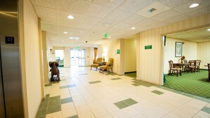 A hotel lobby with a check-in counter, seating area, and a dining area.