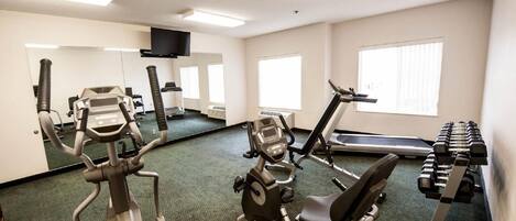 A gym with cardio machines, weightlifting equipment, and a treadmill.