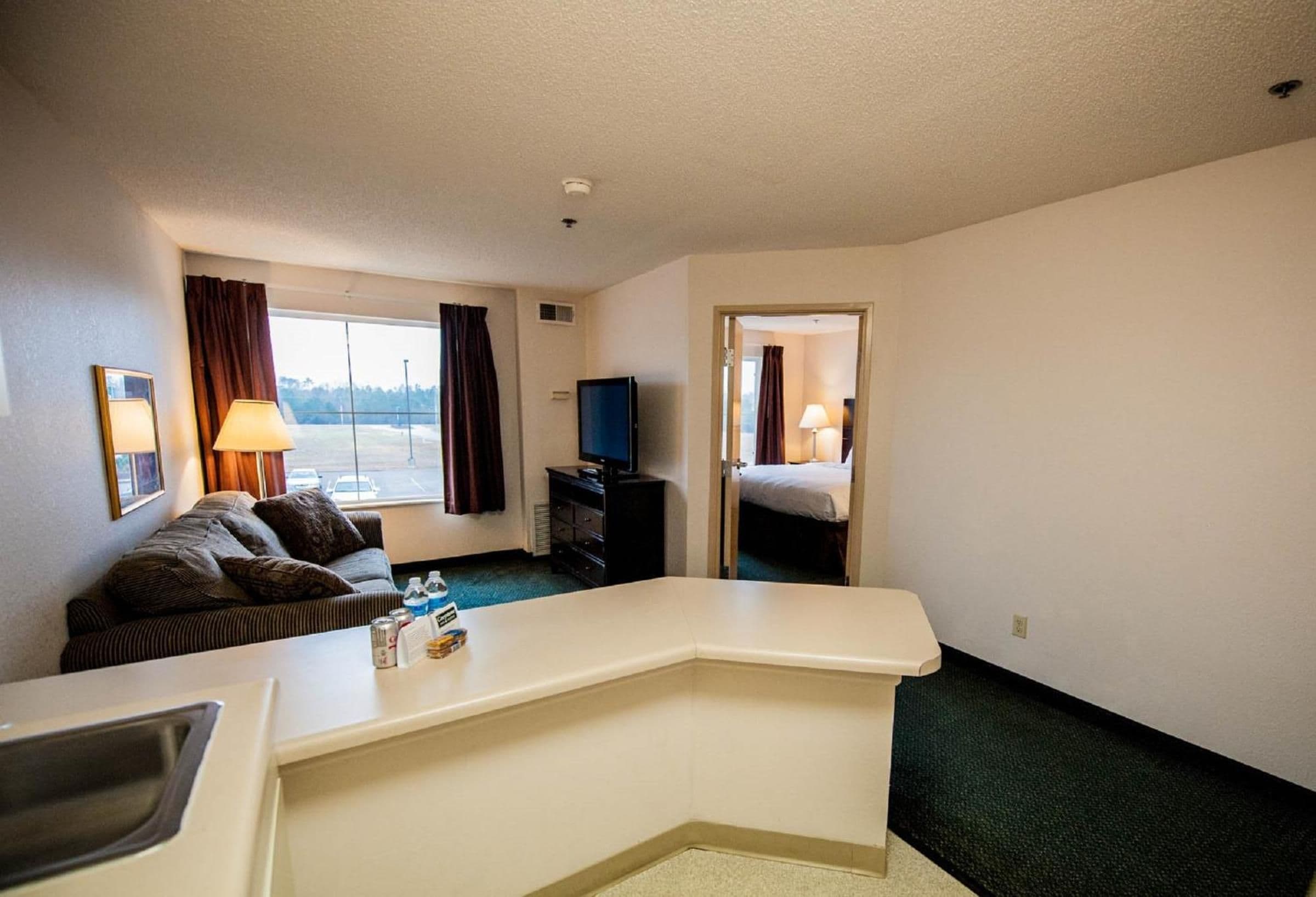 A hotel room with a sofa, a TV, a desk, and a view of the outdoors.