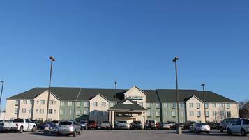 A multi-story hotel with a central entrance and parking lot.