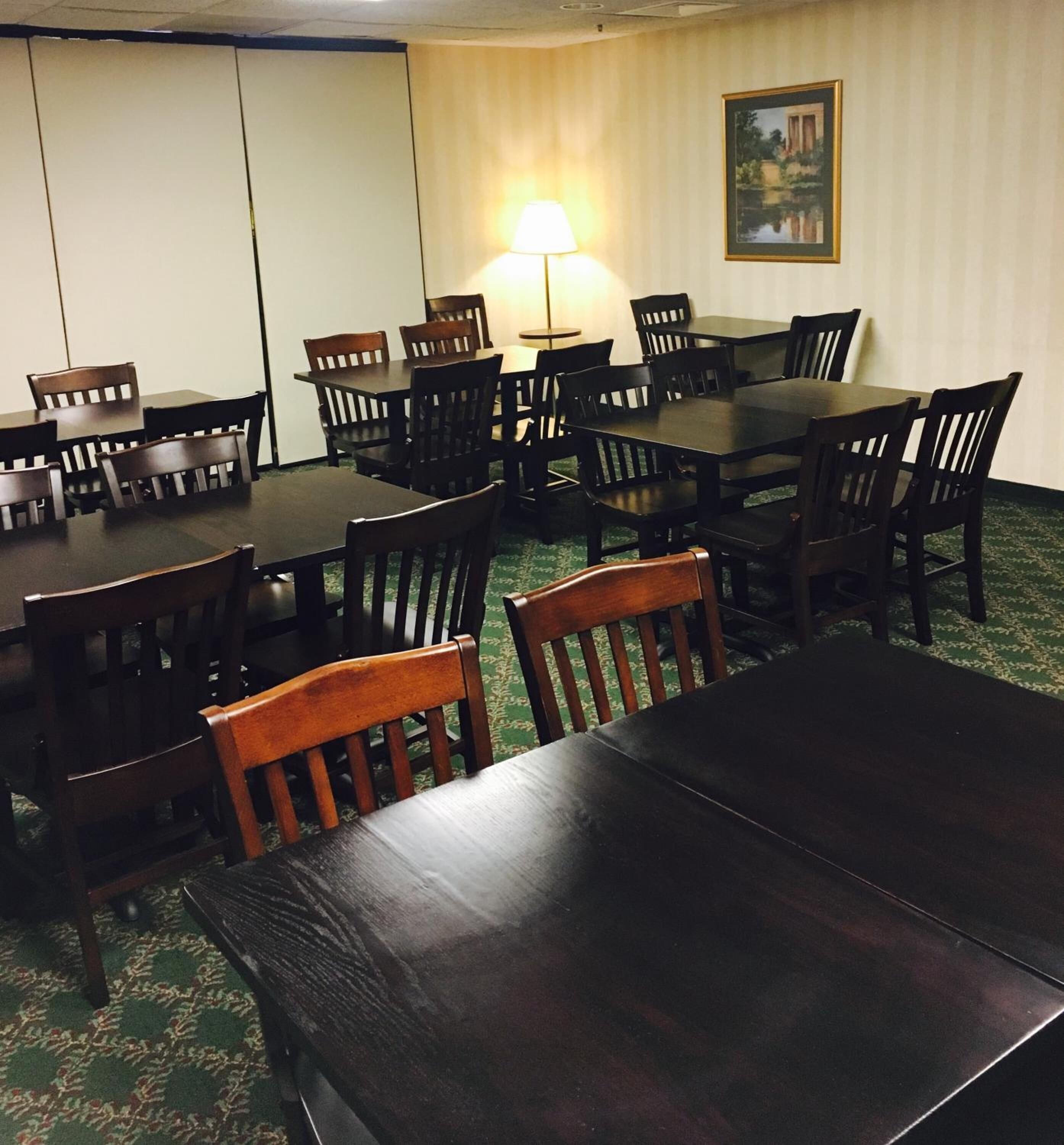 A conference room with multiple tables and chairs, a standing lamp, and a framed picture on the wall.