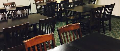 A conference room with multiple tables and chairs, a standing lamp, and a framed picture on the wall.