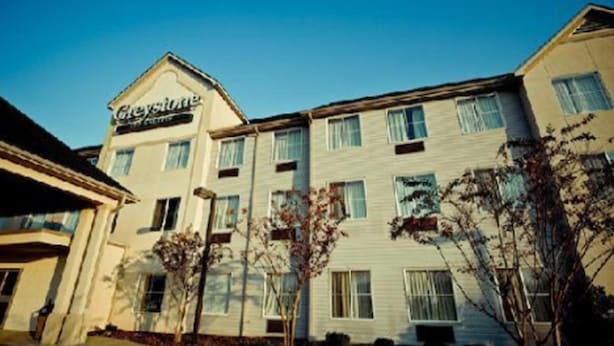 A hotel with a sign reading "Greyhound Inn". It features a multi-story building with several windows and a flat roof.
