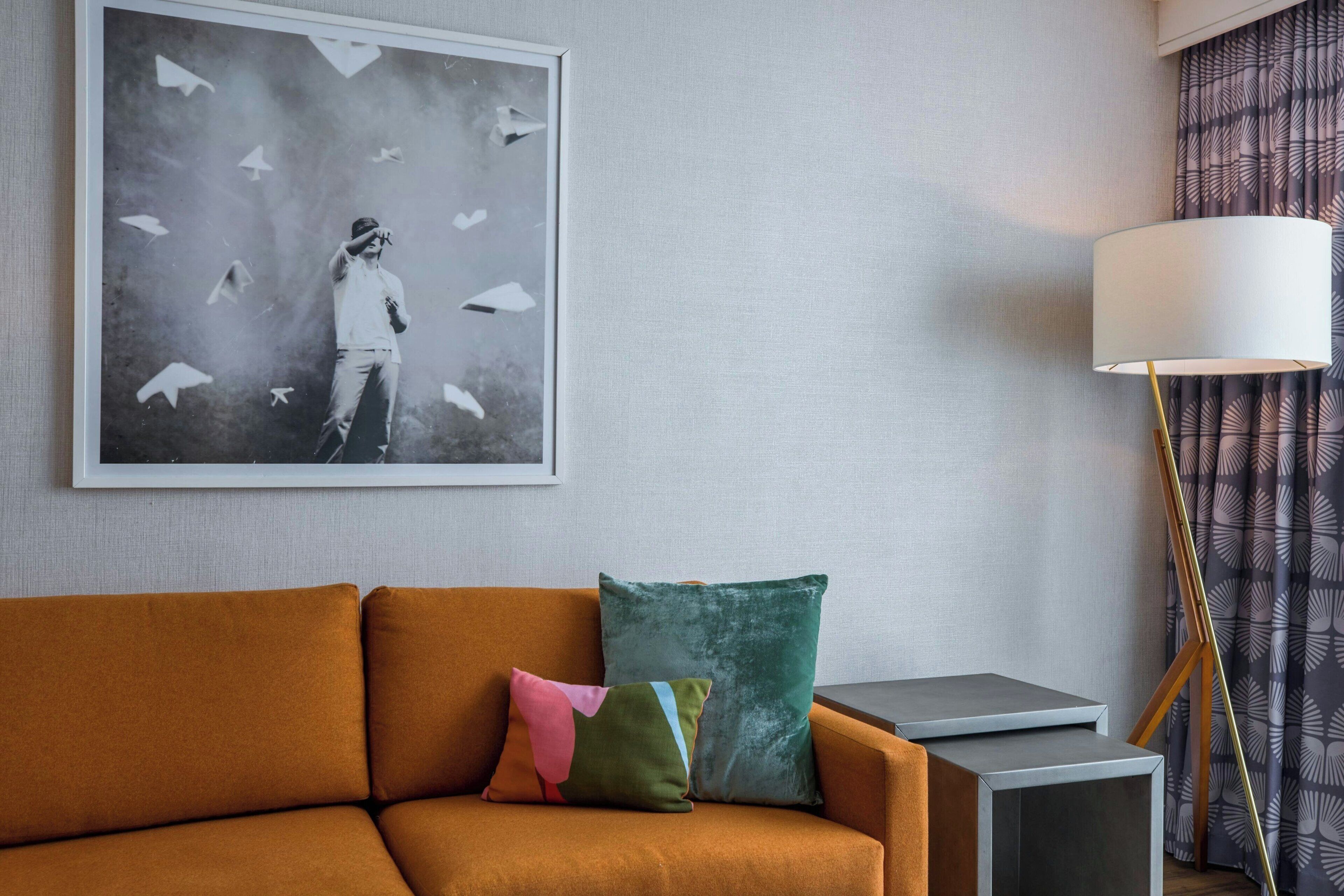 A modern living room with a sofa, pillows, a framed artwork, a floor lamp, and a side table.