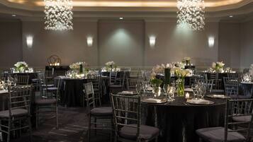 A banquet hall with round tables set for dining, surrounded by chairs.