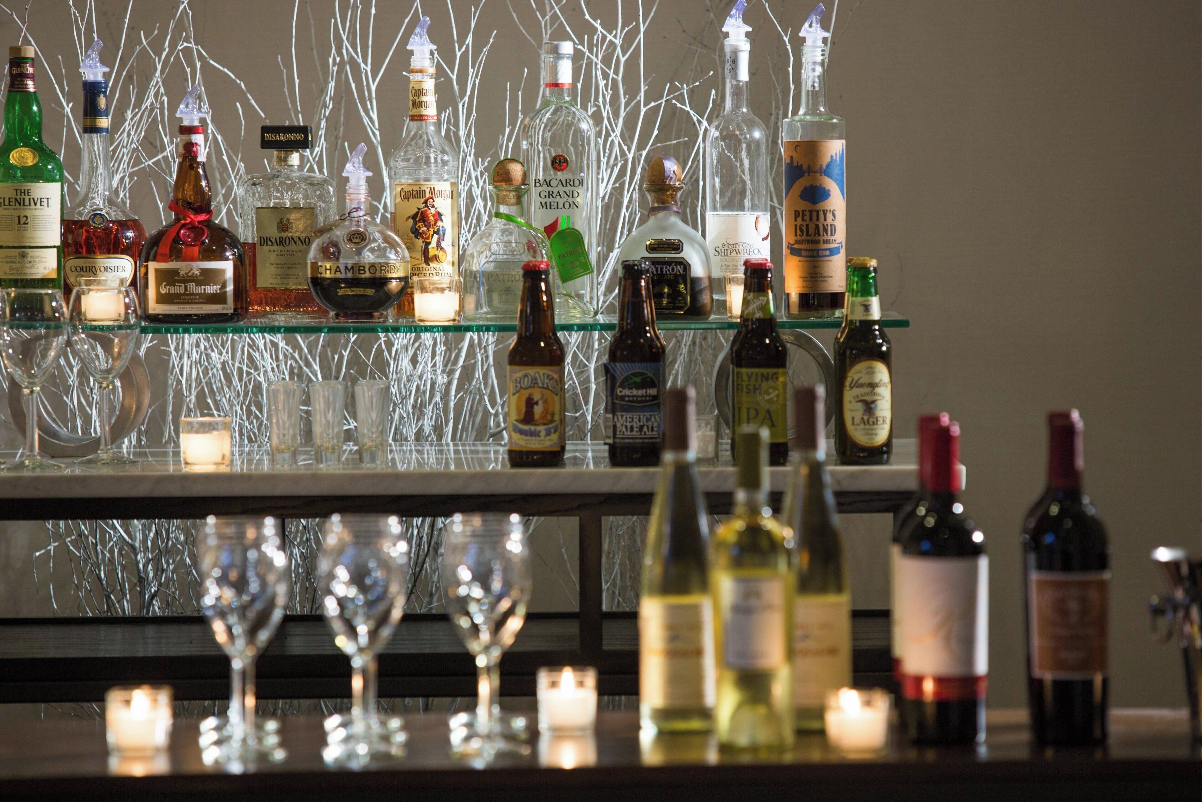 A bar area with various bottles and glasses, including whiskey, wine, and beer.