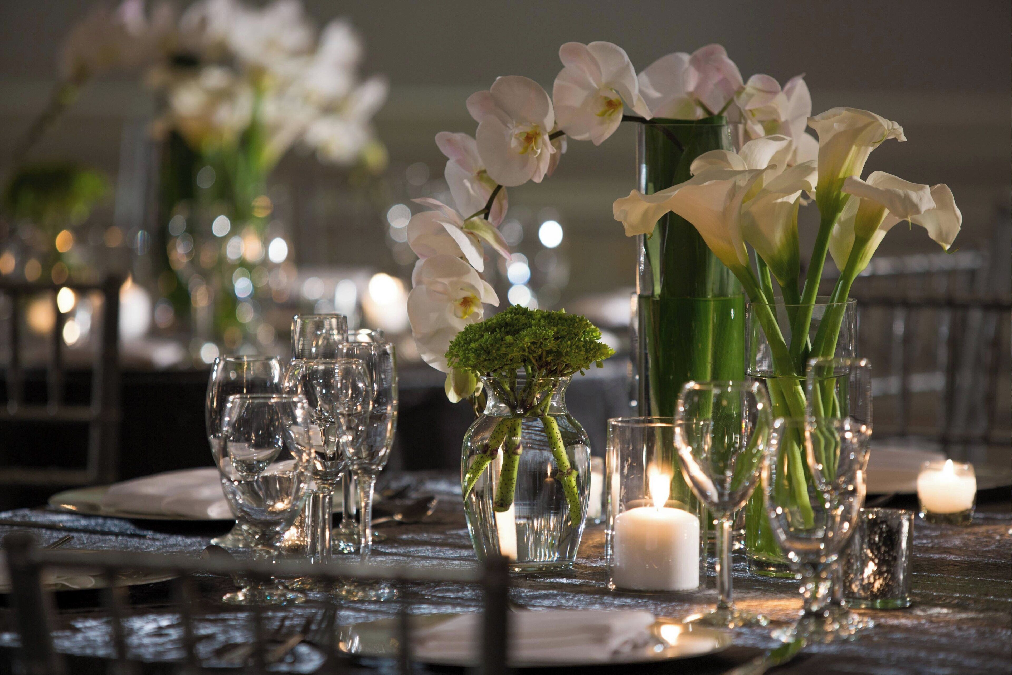 A table set with clear glassware, white flowers, and candles, suggesting a formal dining setting.