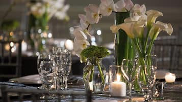 A table set with clear glassware, white flowers, and candles, suggesting a formal dining setting.