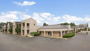 A Days Inn with a parking lot, multiple buildings, and a clear sky. - Days Inn by Wyndham Alexander City (Alexander City)
