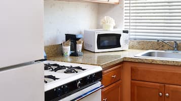 A kitchen with wooden cabinets, a gas stove, a microwave, and a sink.