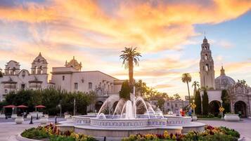 A historic plaza with a central fountain, surrounded by a circular walkway and palm trees.