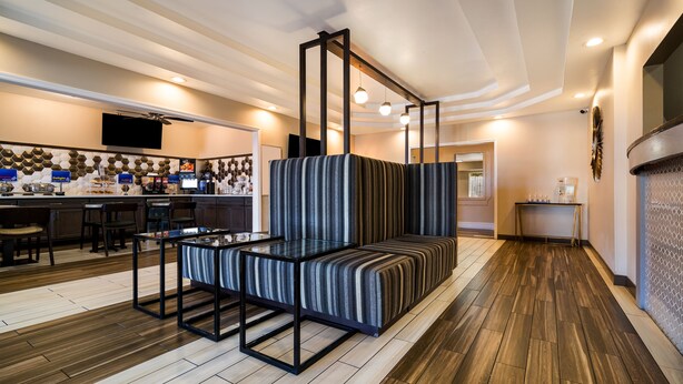 A modern hotel lobby with a seating area, a reception desk, and a television mounted on the wall. - SureStay Plus Hotel by Best Western Topeka Northwest (Topeka)