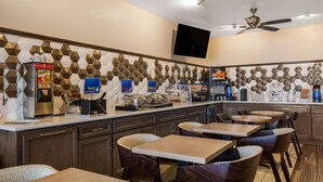 A modern kitchen with a breakfast bar, seating area, and a flat-screen TV. - SureStay Plus Hotel by Best Western Topeka Northwest (Topeka)