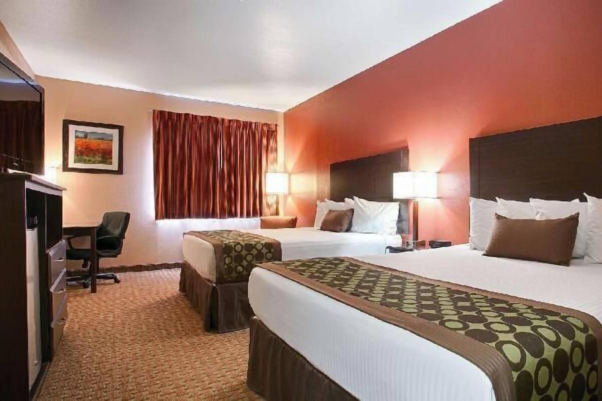 A hotel room with two beds, a desk, and a chair.