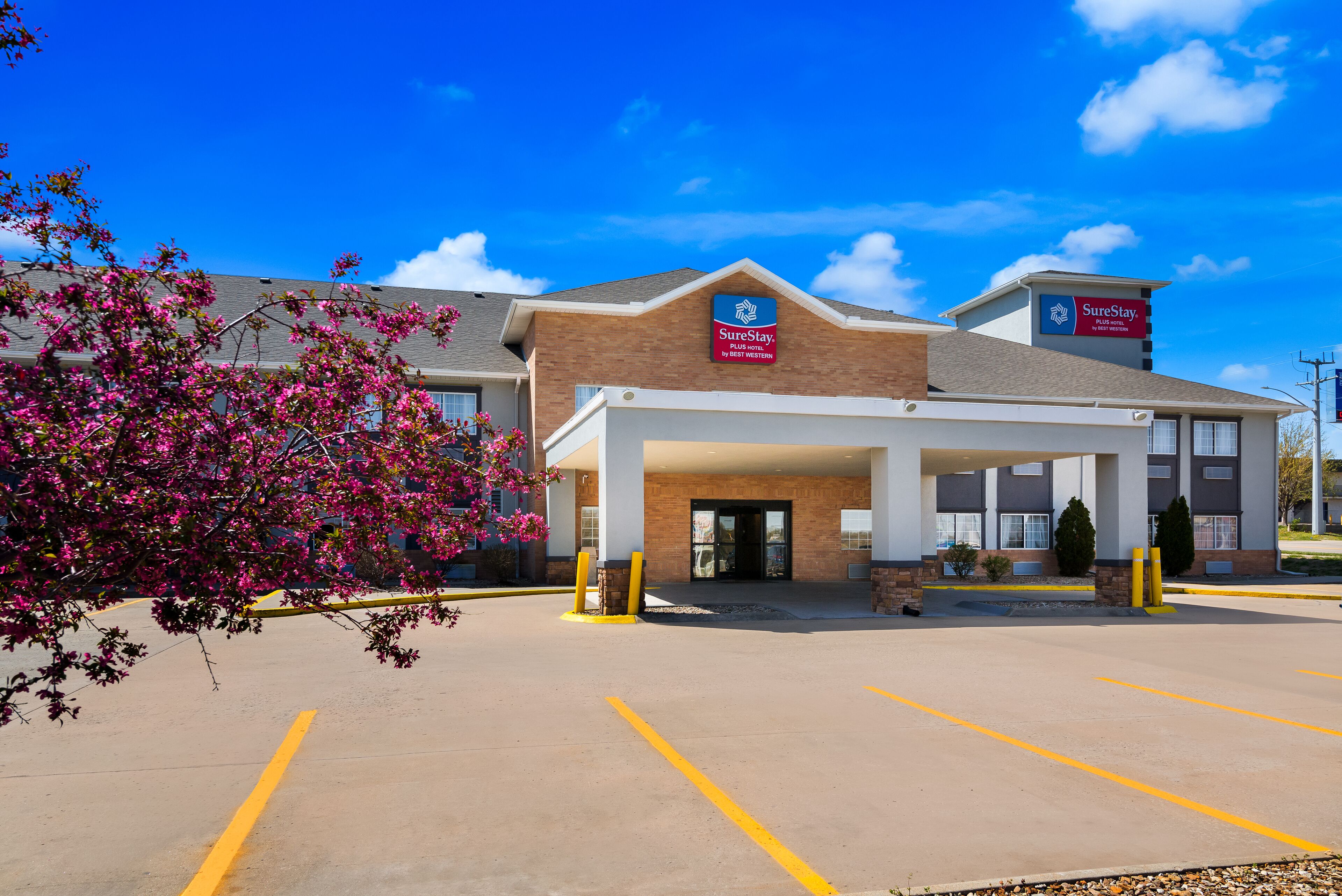 A hotel with a covered entrance, a parking lot, and a sign indicating it is part of the SureStay brand.