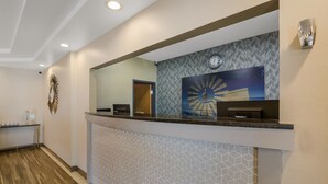 A reception area with a counter, a clock, and a wall-mounted artwork. - SureStay Plus Hotel by Best Western Topeka Northwest (Topeka)