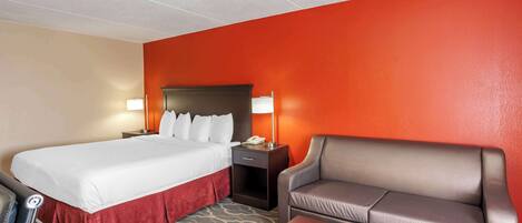 A hotel room with a bed, a desk, a chair, and a nightstand.