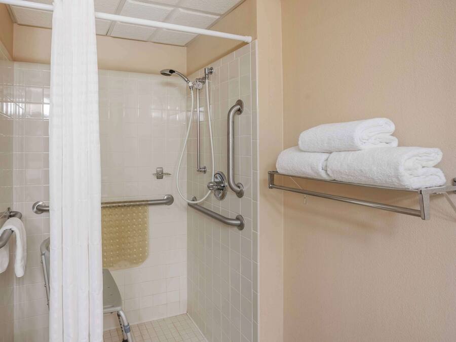 Une salle de bain équipée d’une douche, de barres d’appui, d’un porte-serviettes et d’un sèche-mains.