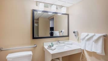 A bathroom with a toilet, sink, and mirror.