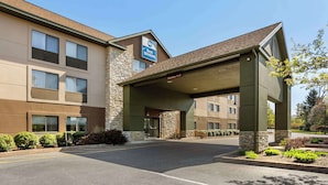 Un hotel Best Western con fachada de piedra, un acceso cubierto y un estacionamiento.
