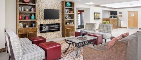 A spacious living area with a fireplace, comfortable seating, a flat-screen TV, and a bookshelf.