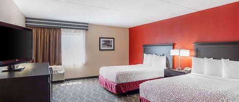 A hotel room with two beds, a TV, a desk, and a lamp.