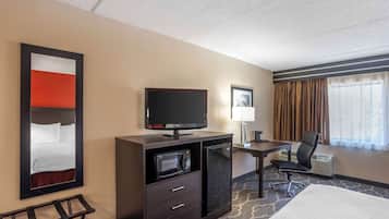Ein Hotelzimmer mit Bett, Schreibtisch mit Computer, Fernseher, Mikrowelle und Stuhl.