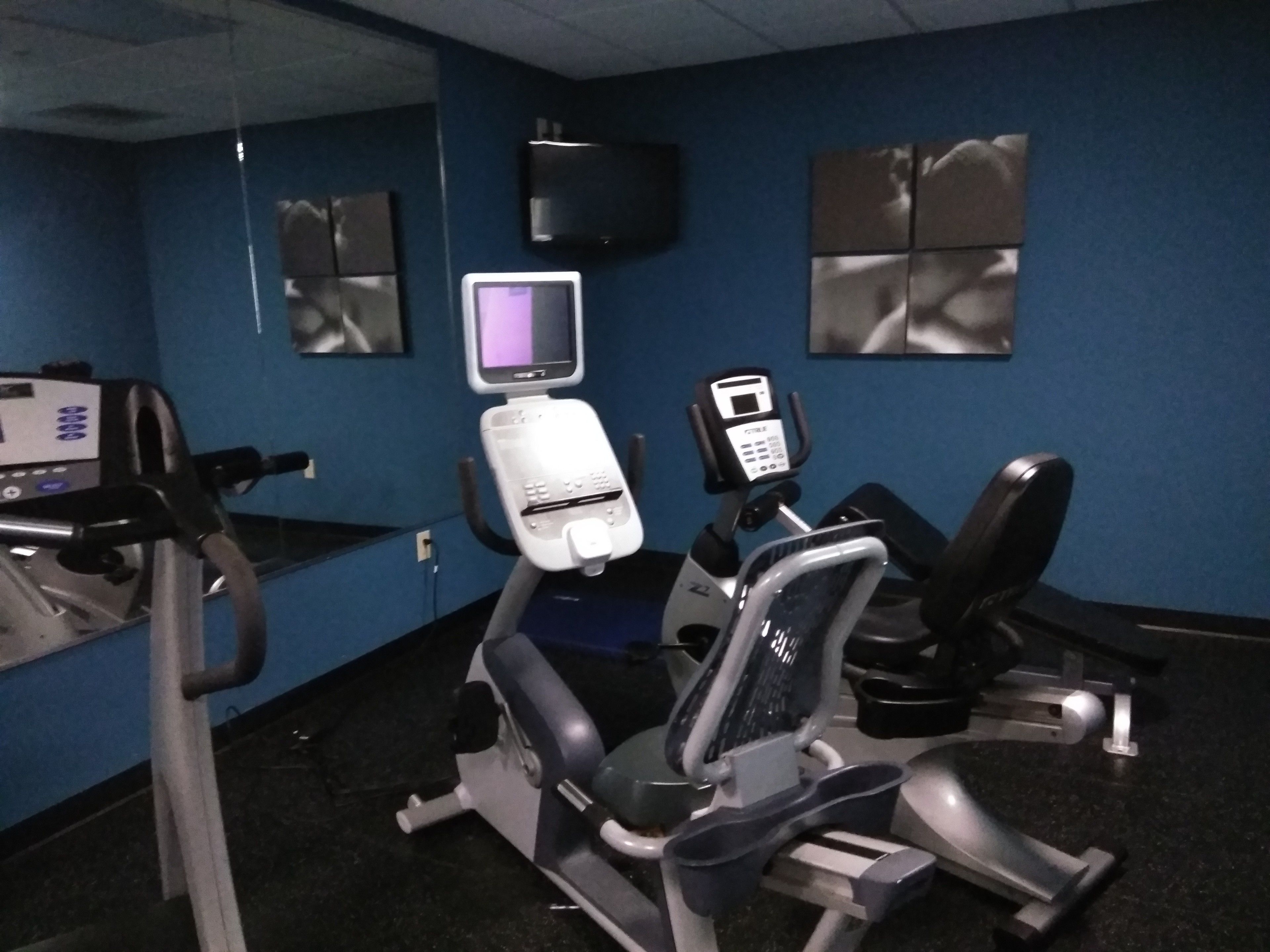 Een sportschool met trainingsapparatuur, een televisie en een spiegel.