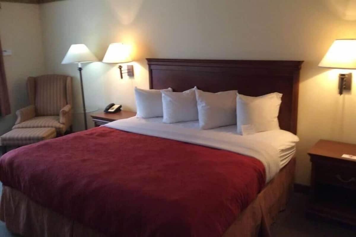 Een hotelkamer met een bed, twee bedlampen, een stoel, een nachtkastje en een telefoon.