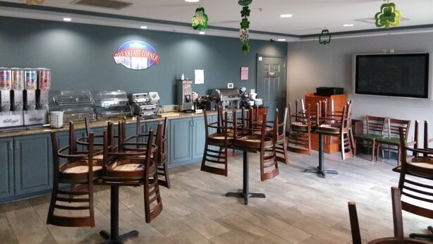 A breakfast area with a counter, coffee machines, and seating. - Baymont by Wyndham Clinton (Clinton)