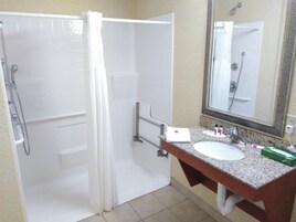 Un baño con ducha, lavamanos y espejo.