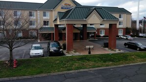 A Baymont Inn & Suites building with a parking lot, a red fire hydrant, and a tree. - Baymont by Wyndham Clinton (Clinton)