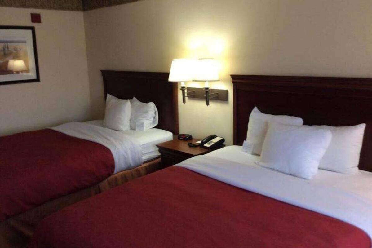 Een hotelkamer met twee bedden, een nachtkastje met een lamp en een telefoon.