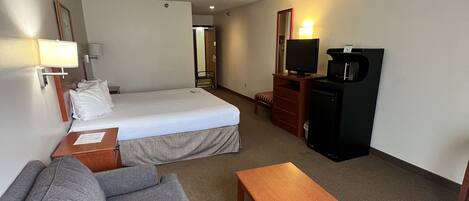 A hotel room with a bed, a sofa, a TV, and a desk.