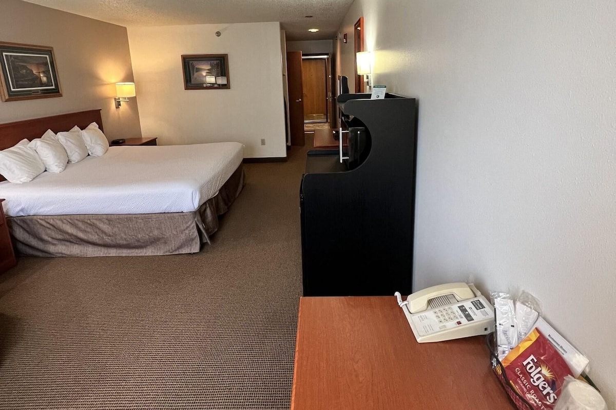 A hotel room with a bed, a desk with a telephone, and a coffee machine.