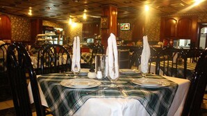 Ein Restaurant mit kariertem Tischtuch, weißen Servietten und einem Fernseher im Hintergrund.