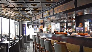 Eine Bar mit einer Theke, Hockern sowie einer Auswahl an Flaschen und Snacks.