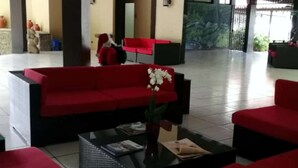 A spacious lobby with red sofas and a black coffee table, featuring a large pillar and a tiled floor. - Best Western El Sitio Hotel (Liberia)