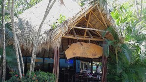 A thatched-roof structure labeled "Rancho El Sitio" with outdoor seating and tropical vegetation. - Best Western El Sitio Hotel (Liberia)