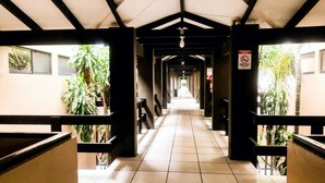A corridor with tiled flooring, black railings, and potted plants. - Best Western El Sitio Hotel (Liberia)