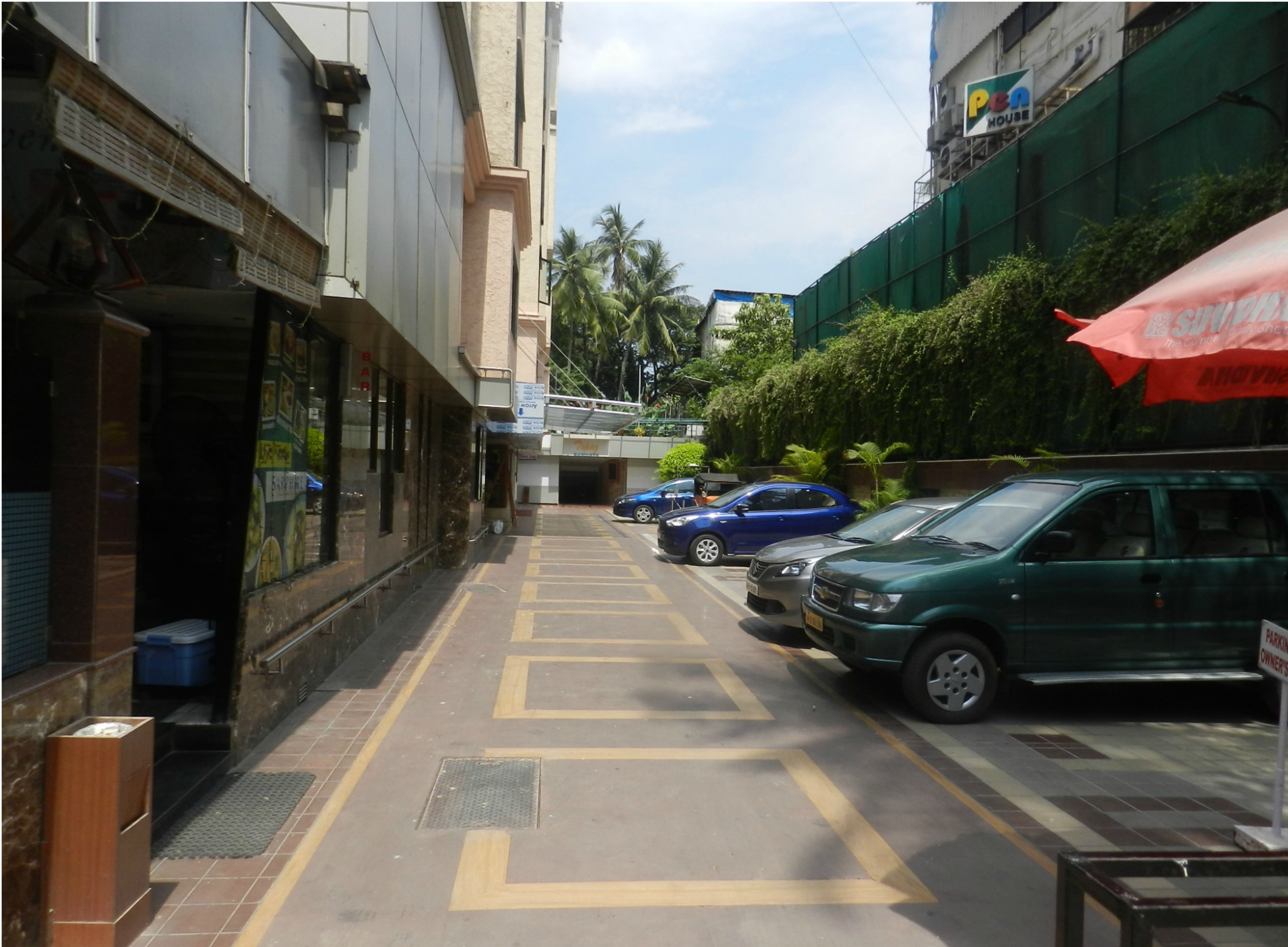 Una calle estrecha con automóviles estacionados y un edificio con un letrero que dice "PEN HOUSE".