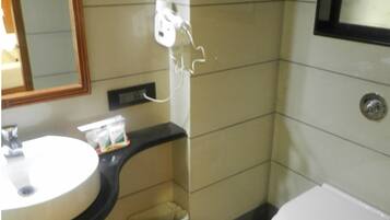 Un baño con lavamanos, espejo, inodoro y cubo de basura.