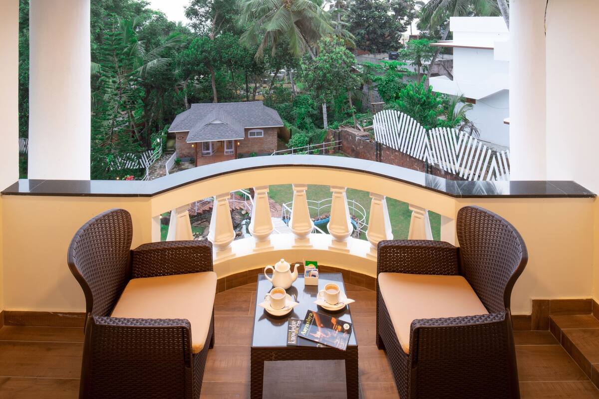 A balcony with wicker furniture, a table with a teapot, cups, and a magazine.
