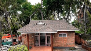 A small brick house with a tiled roof, a front porch, and a visible name sign. - Swagath Holiday Resort (Neyyattinkara)